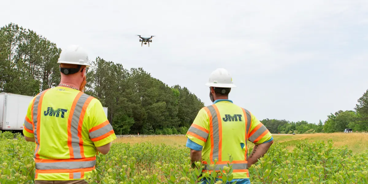 JMT employees in field looking at drone
