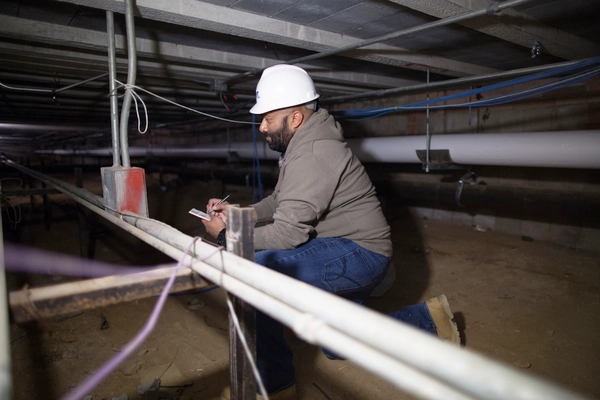 Peron wearing a hard hat in an interstitial space taking notes