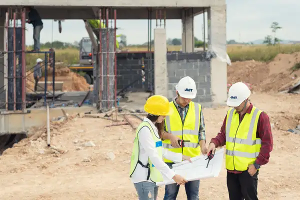 Three employees looking at plans on a job site