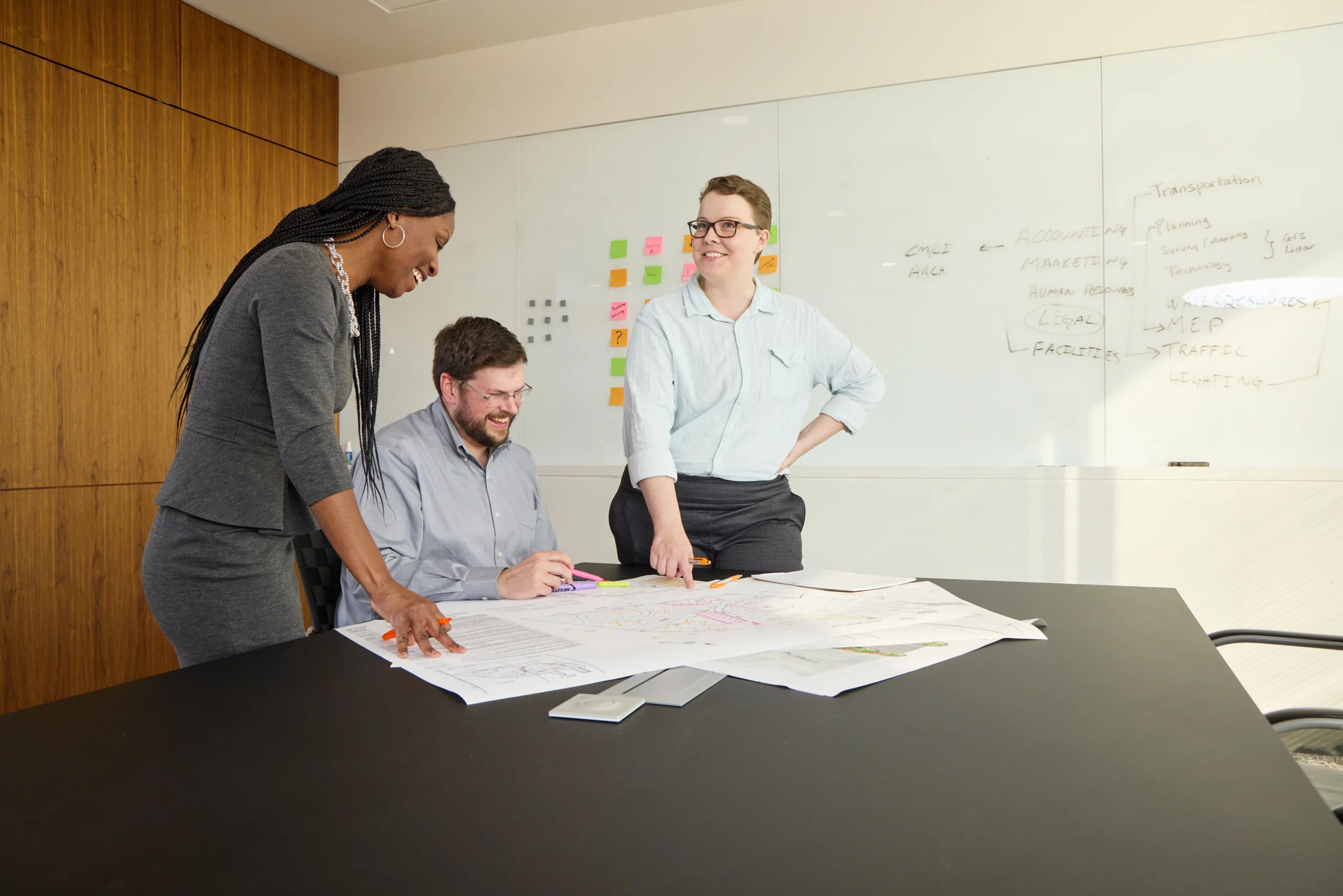 Three employees at a desk looking over plans